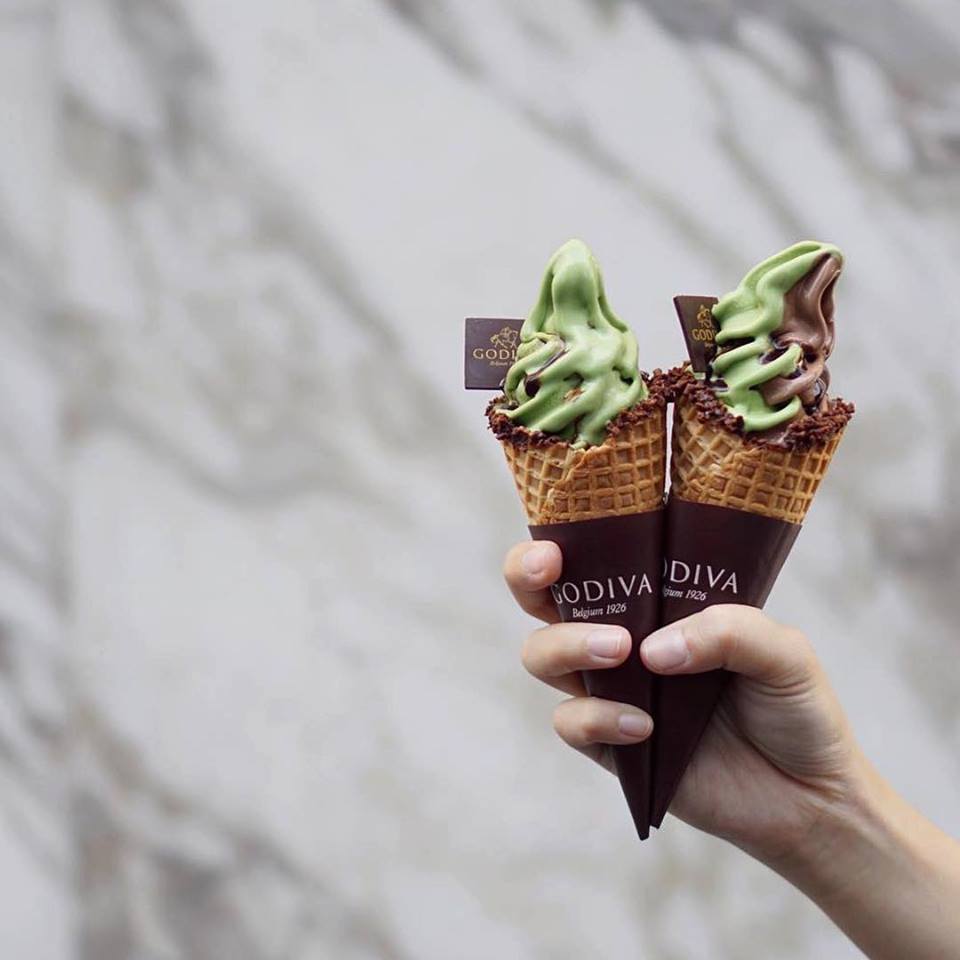 2 cones of Godiva match ice cream in 1 hand