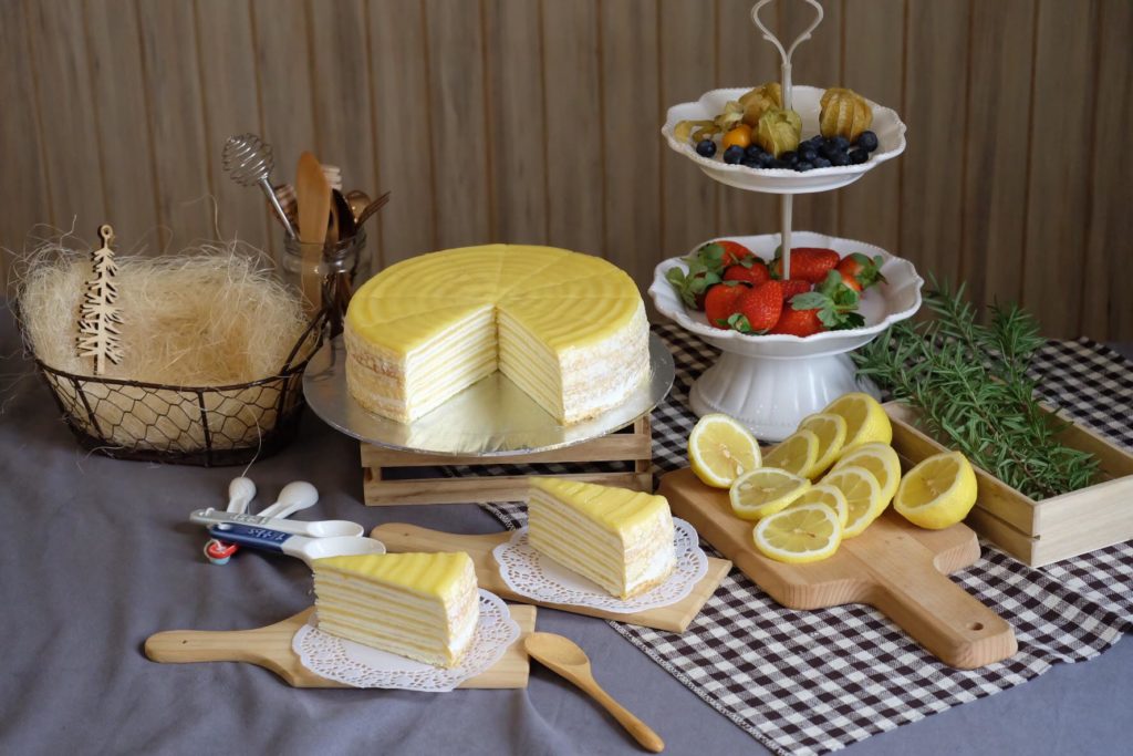 Lemon layer crepe cake with tray on side and lemon slices around