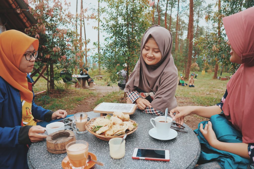 3 muslim ladies dining outdoors with trees in background