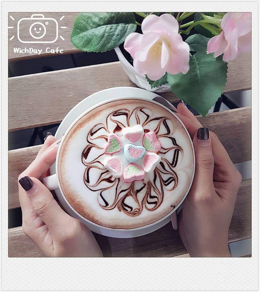 Hot chocolate with art on top held in hands