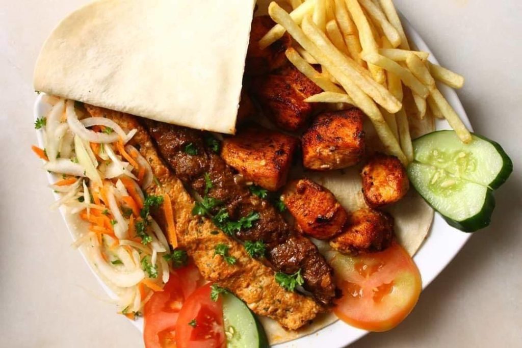 Kebab and side dishes on white plate