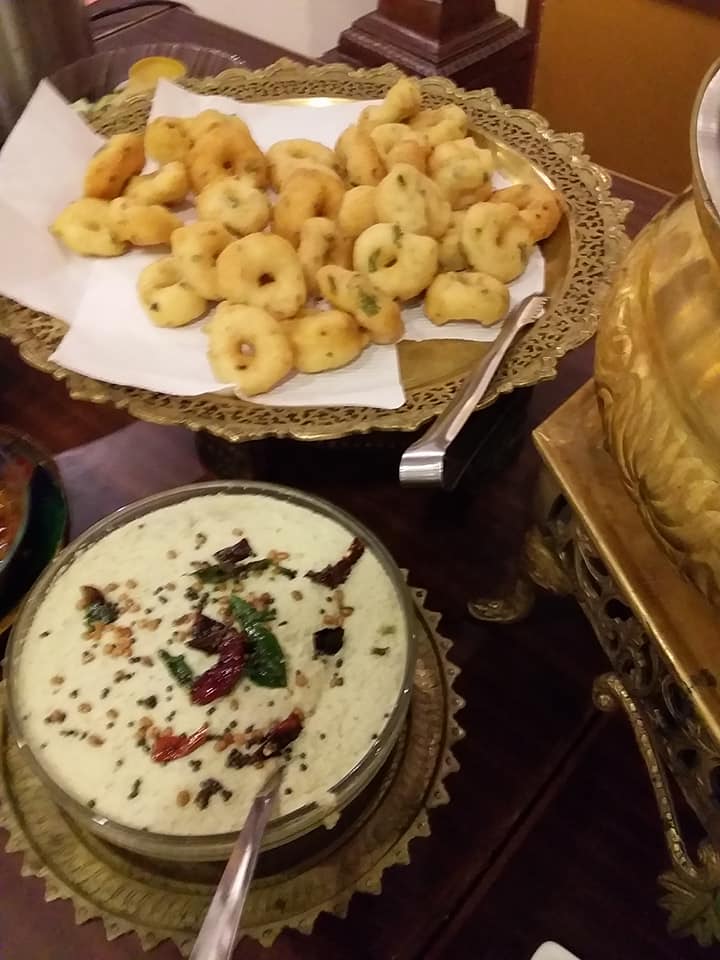 Creamy curry with yogurt next to basket of vadai