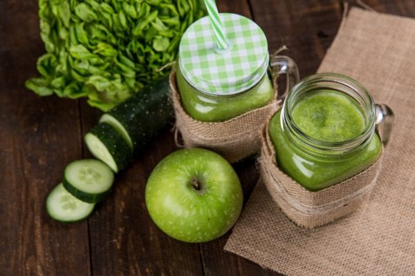 Green juice with cucumber slices and green apples