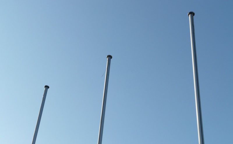 Three flagpoles against a blue sky