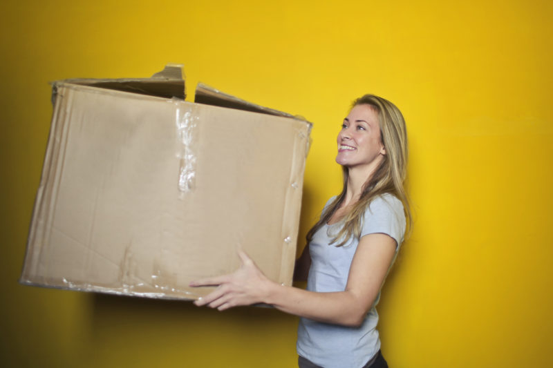Woman carrying big cardboard box for house moving