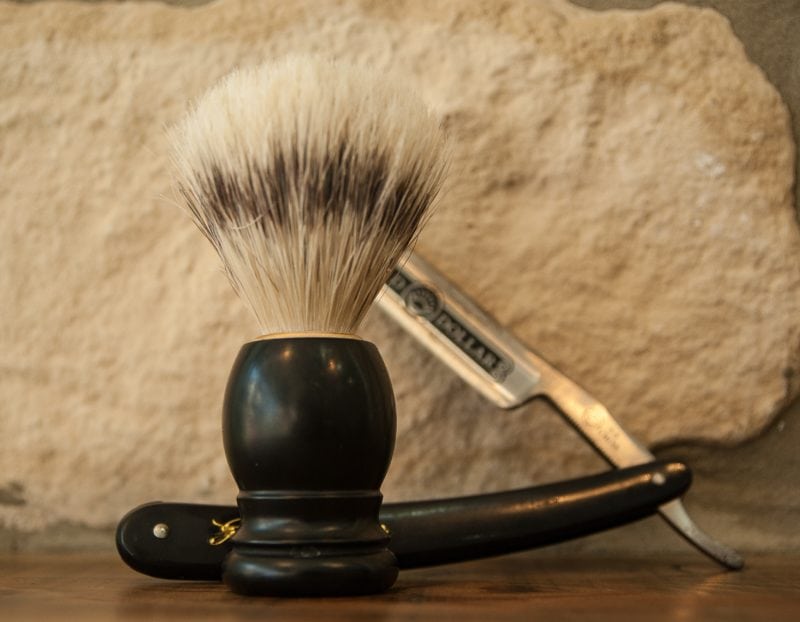 Old school shaving kit with brush, razor on white textured background at Autocutt Barbershop