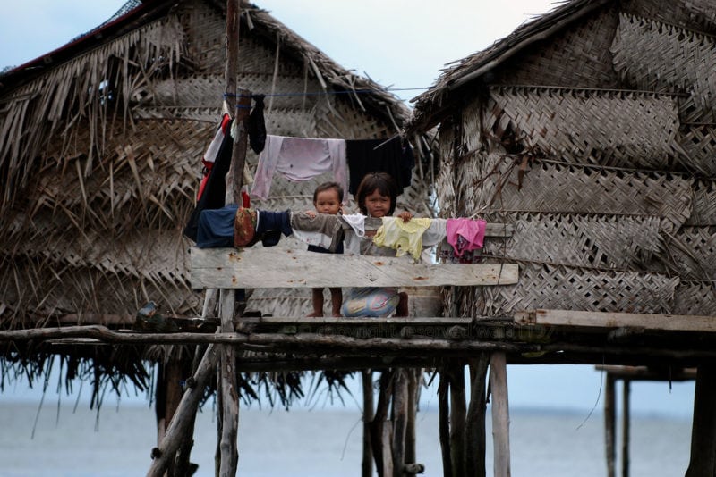 young kids standing on rattan houses