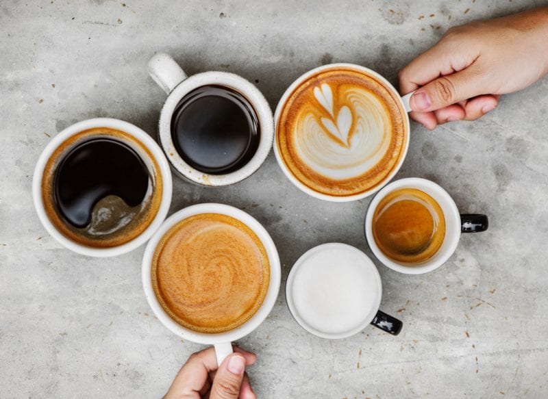 cups of coffee in different cups and one with latte art