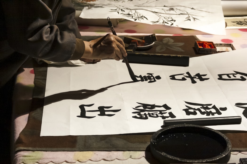 man writing chinese words with brush