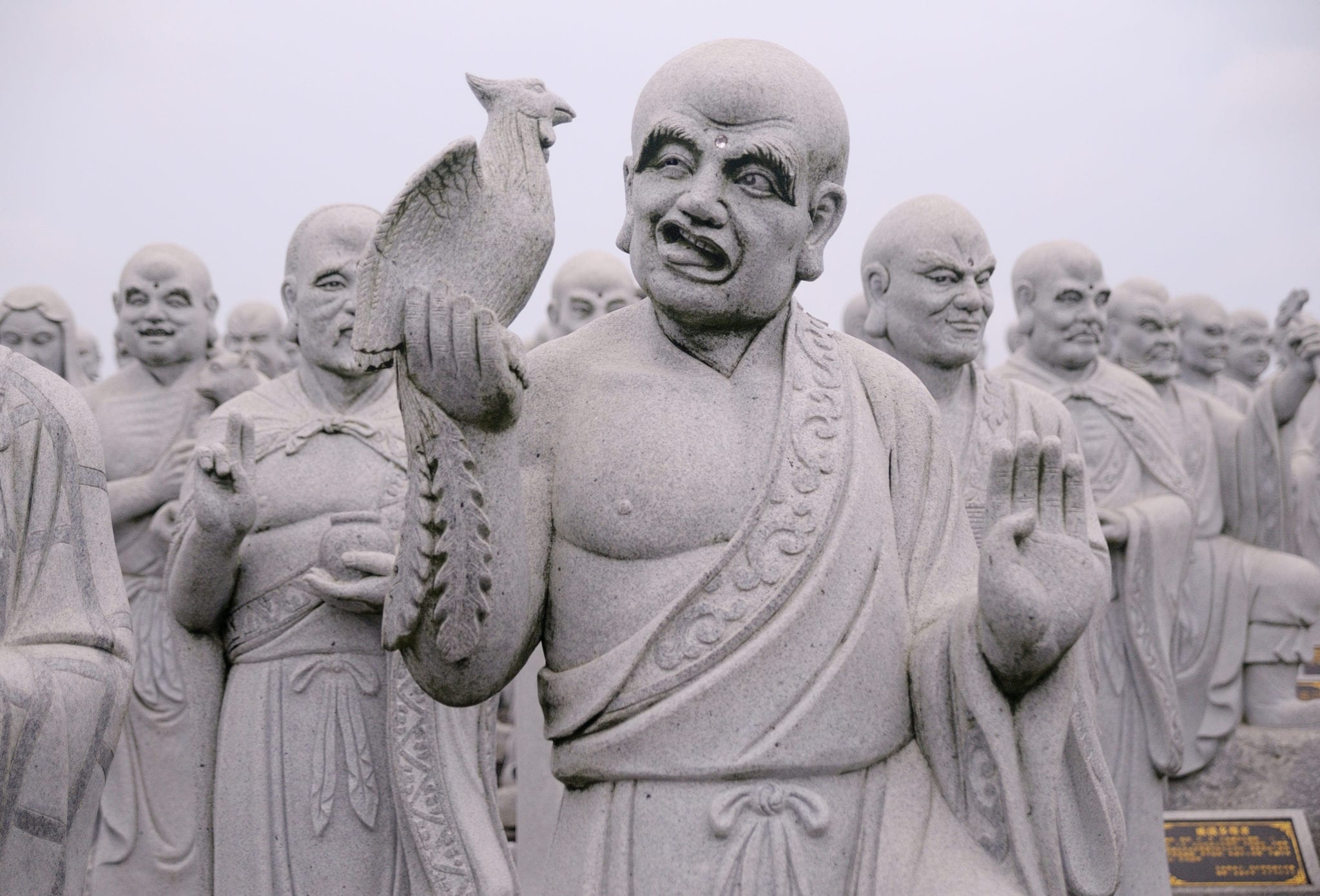 stone buddha statue with bird perched on hand