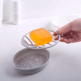 person holding soap dish with bar of orange soap